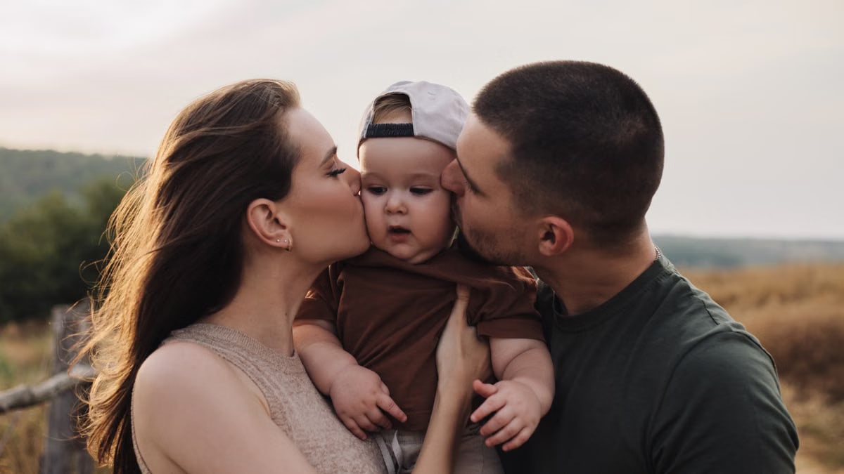 A heartwarming family moment captured during sunset with parents and toddler outdoors.